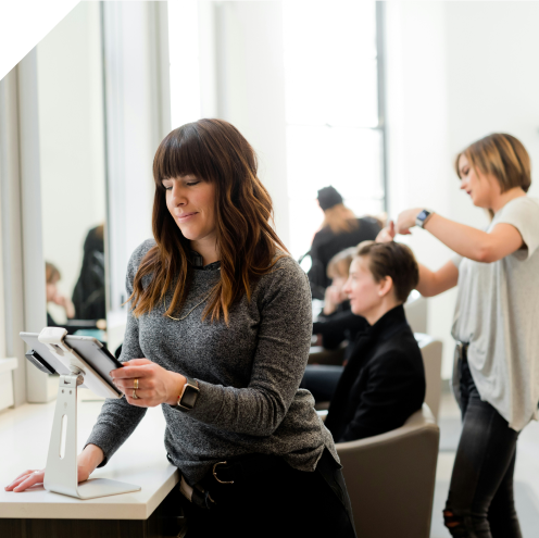 Cheffe d'entreprise artisanale, salon de coiffure, qui tient une tablette